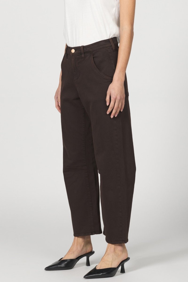 Person wearing dark brown pants and black shoes on a white background