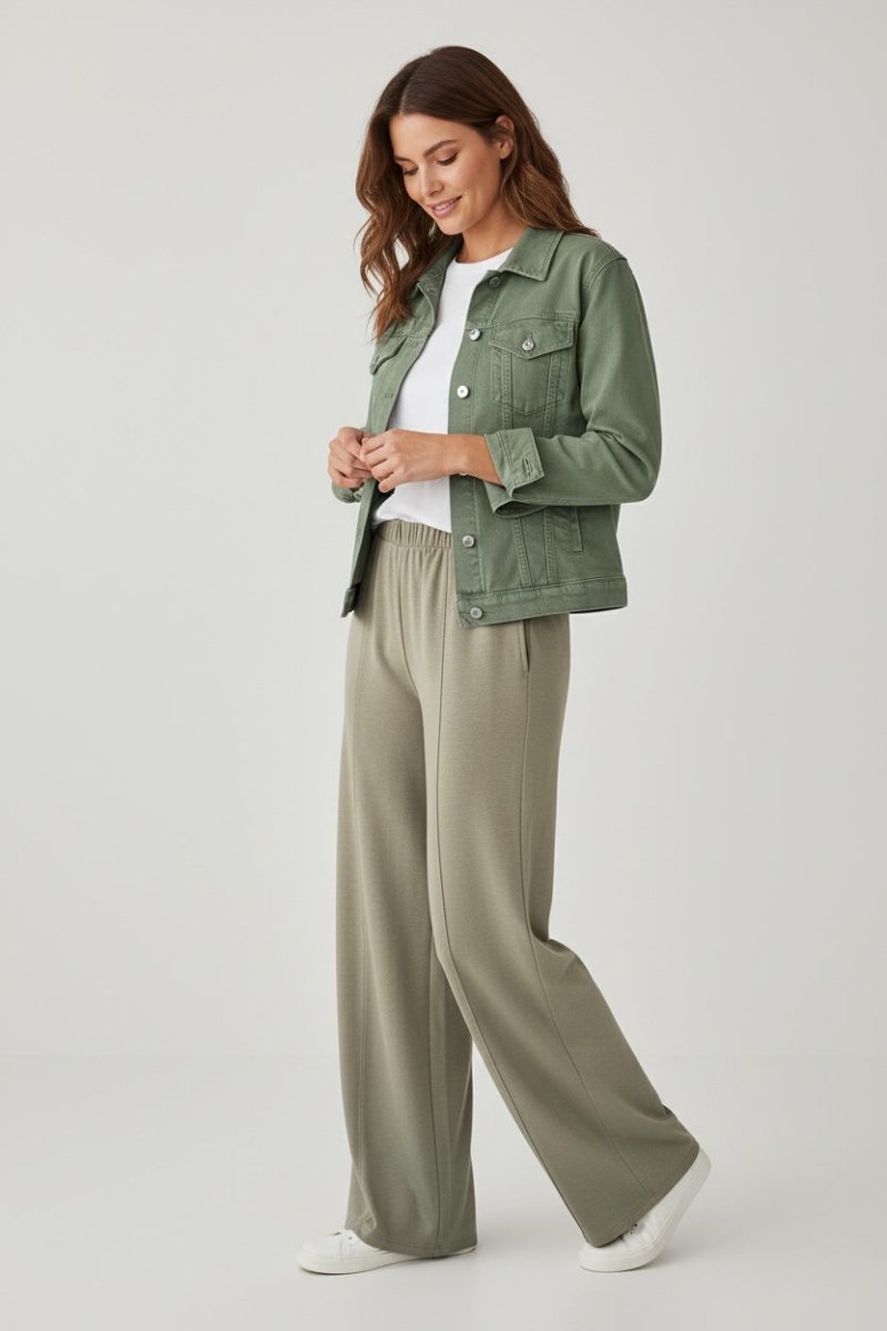 Woman wearing a green jacket and beige pants on a white background