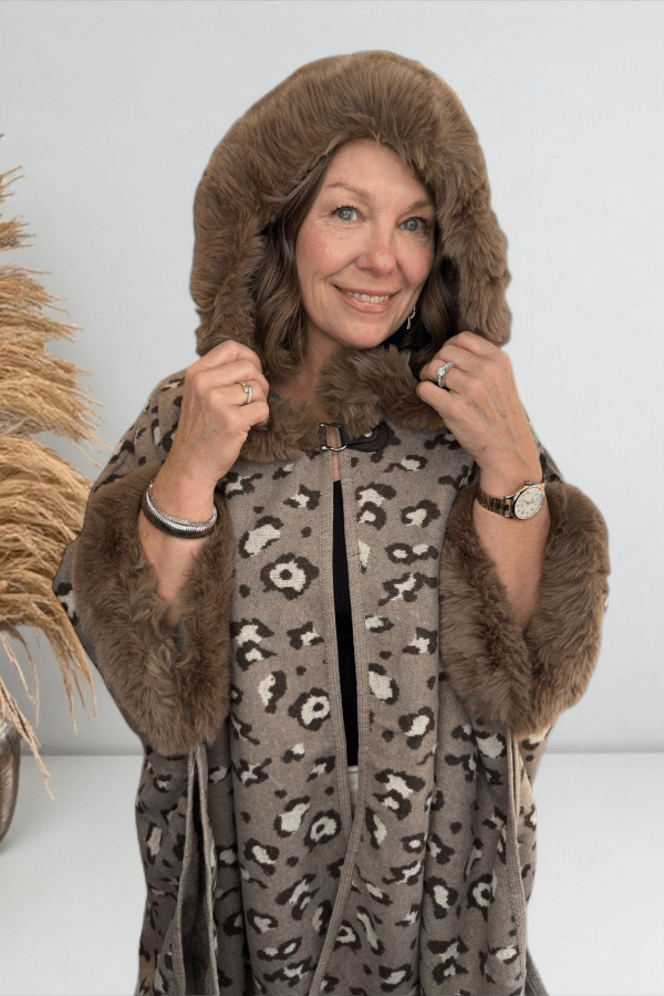 Woman wearing a leopard print coat with fur trim against a white background