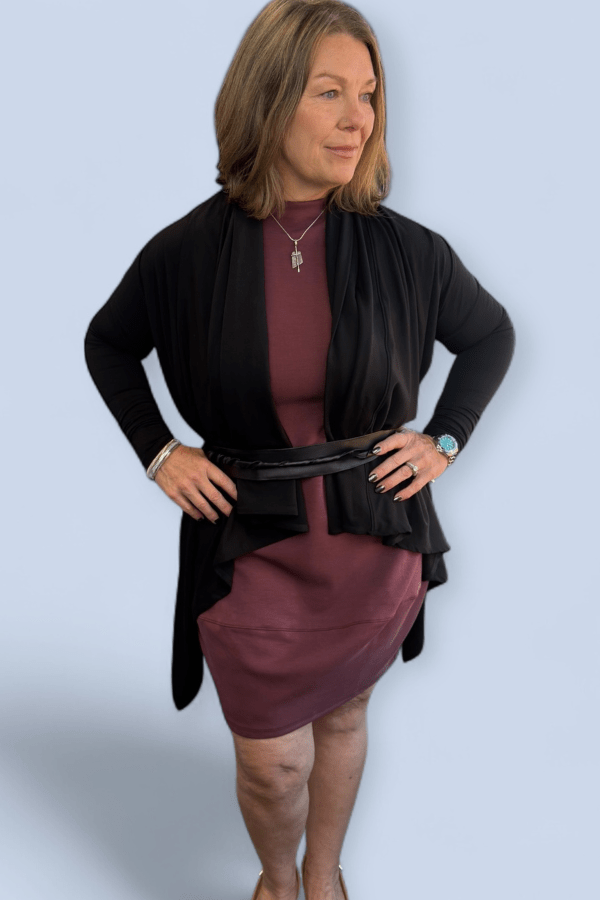 Woman wearing a black cardigan over a burgundy dress on a light blue background