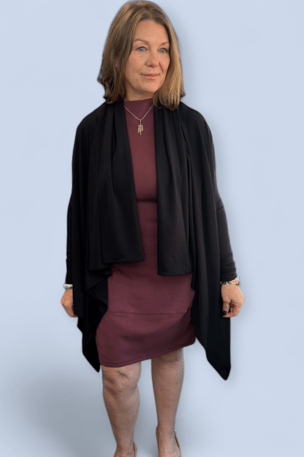 Woman wearing a black cardigan over a burgundy dress on a light blue background