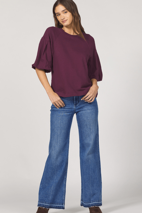 Woman wearing a purple blouse and blue jeans on a white background