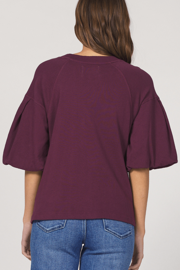 Person wearing a burgundy top and blue jeans on a plain background