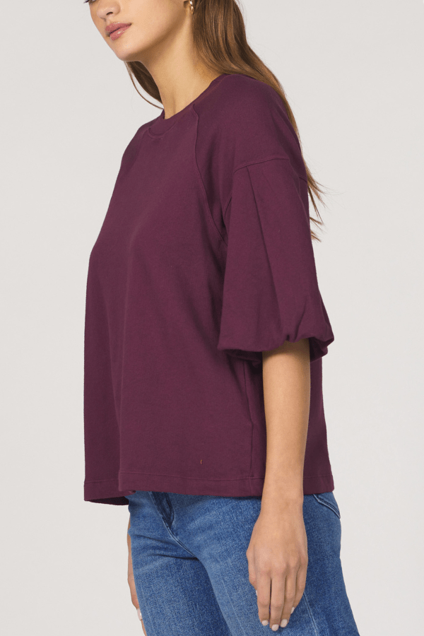 Person wearing a purple top and blue jeans on a plain background