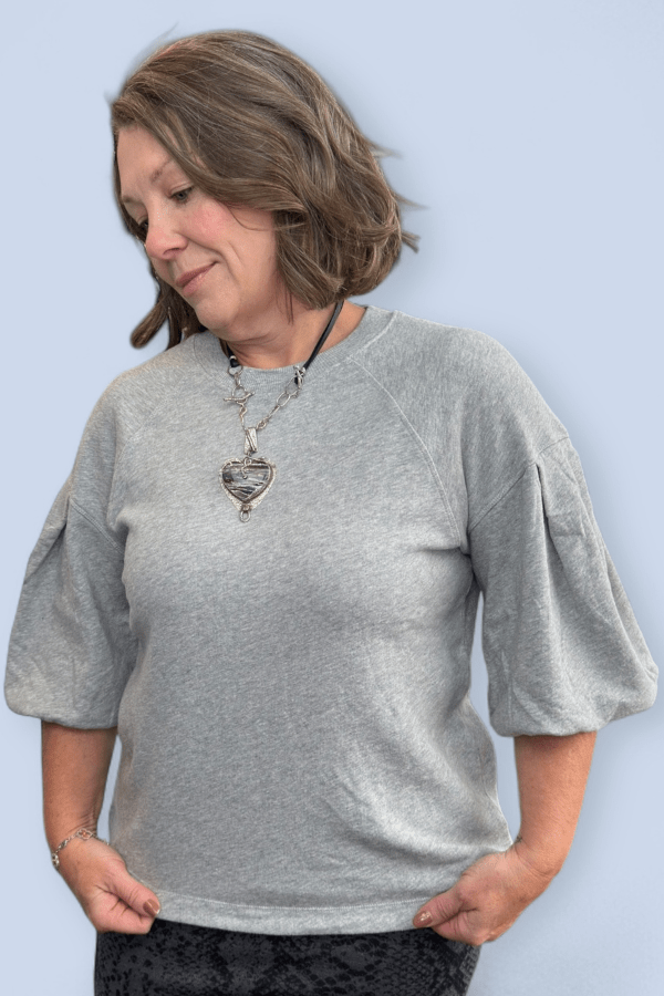 Woman wearing a gray sweater with a plain background