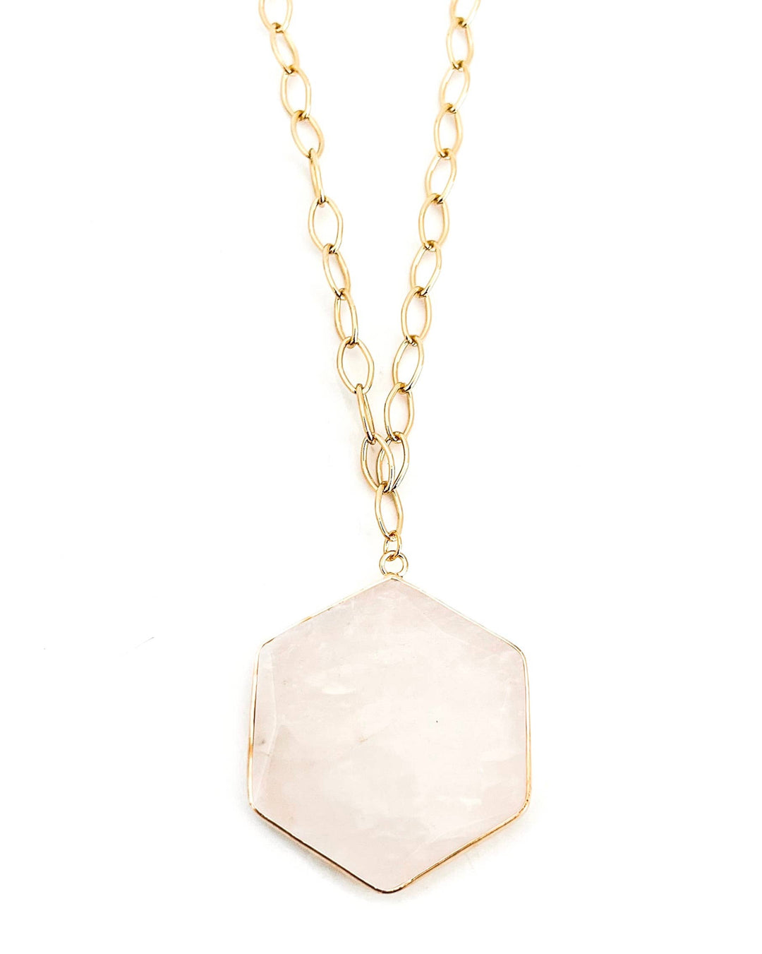 Necklace with a hexagonal beige pendant on a gold chain against a white background