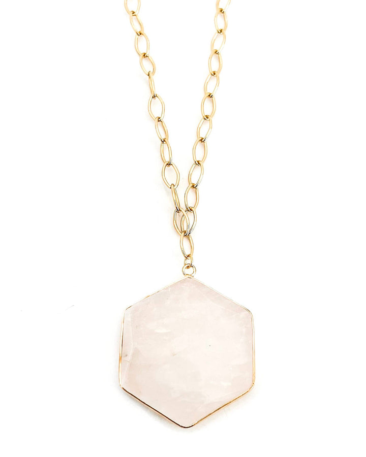 Necklace with a hexagonal beige pendant on a gold chain against a white background