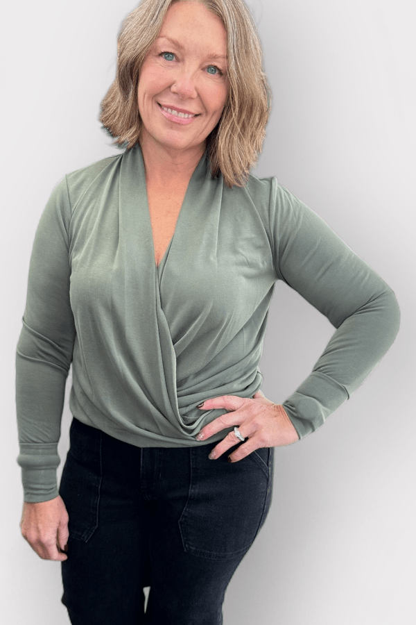 Woman wearing a green long-sleeve top with a white background