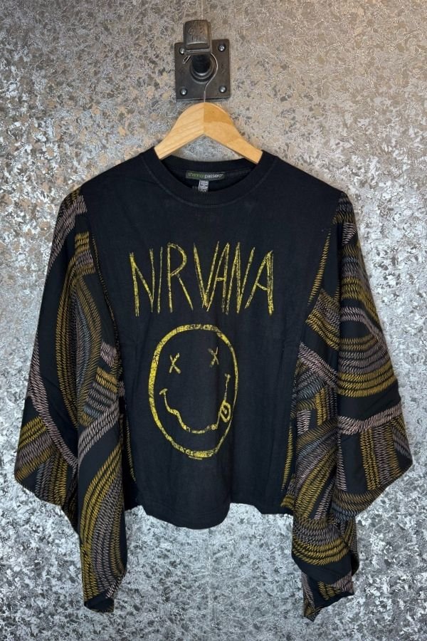 Black sweater with Nirvana logo on a hanger against a textured wall.