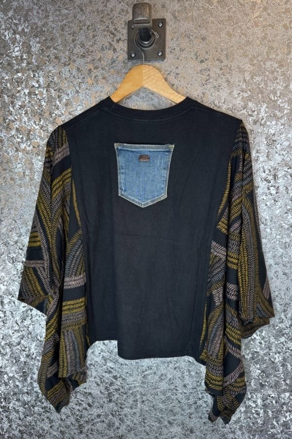 Black shirt with denim pocket and patterned sleeves on a textured surface