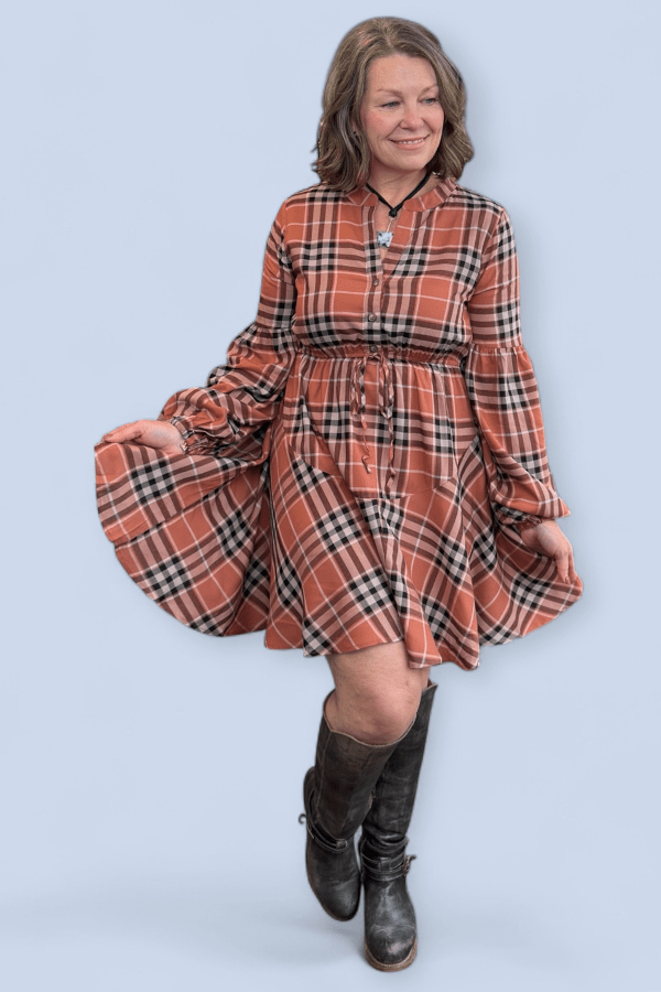 Woman wearing a plaid dress with long sleeves on a light blue background