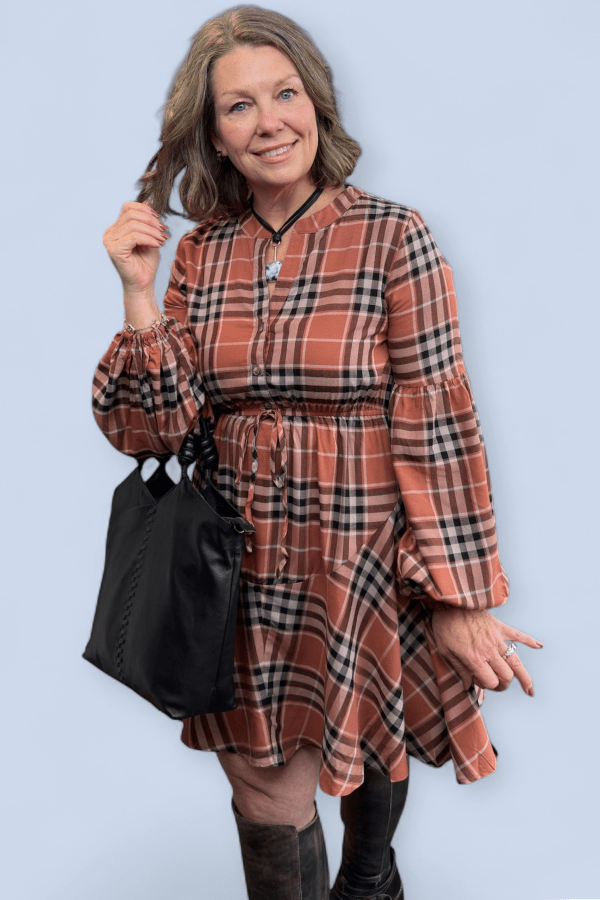 Woman wearing a plaid dress with long sleeves against a light blue background