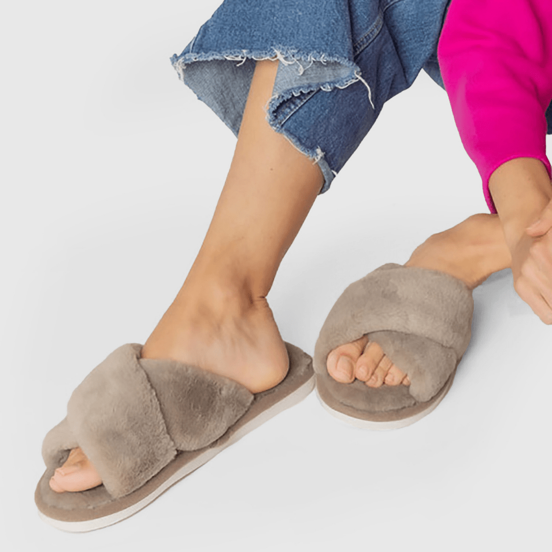 Faux fur criss cross slippers worn on a women with a white background.