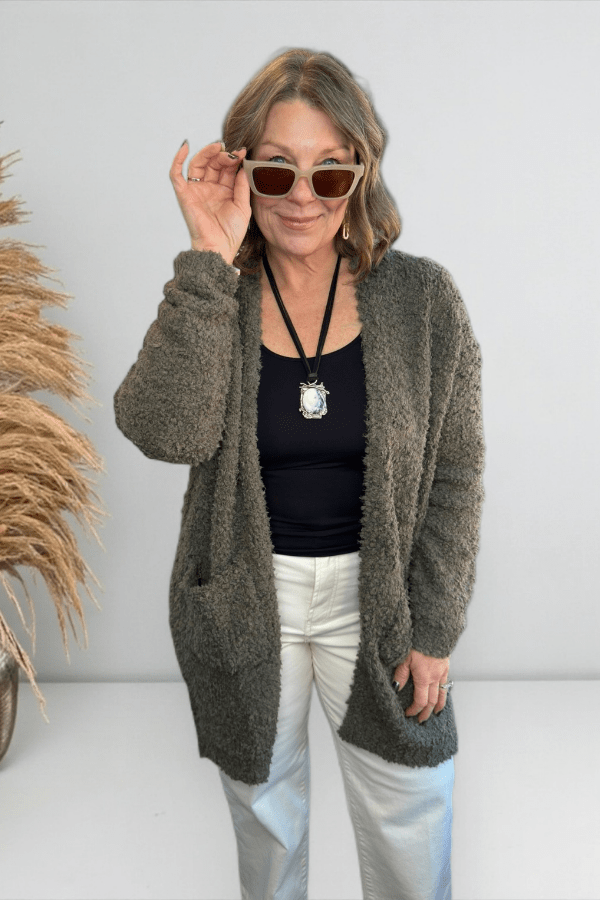 Olive popcorn knit longline cardigan with open front and patch pockets worn with sunglasses.