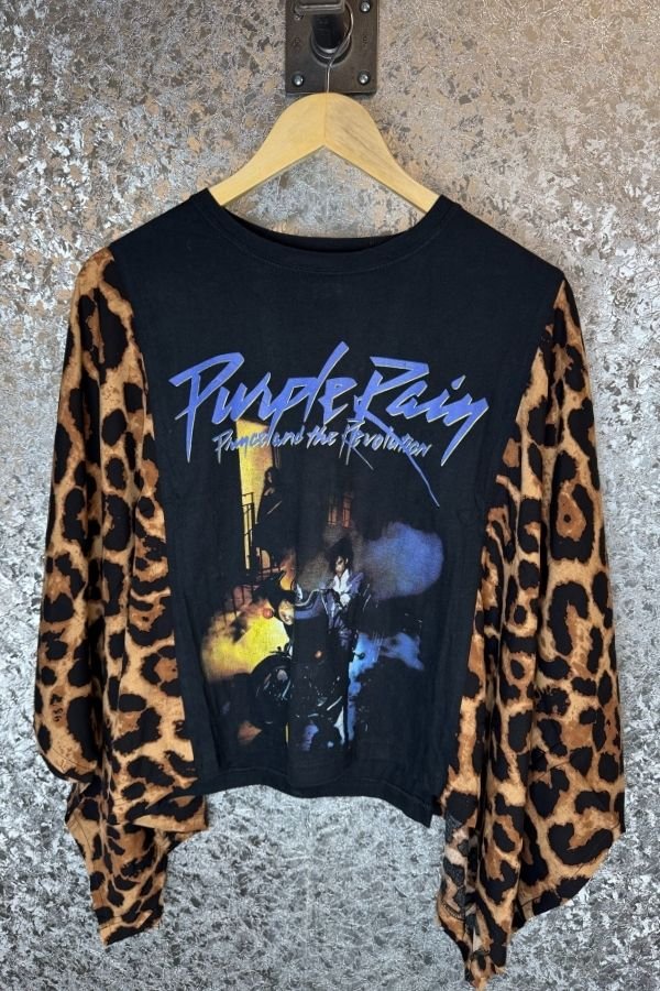 Black graphic t-shirt with 'Purple Rain' design and leopard print sleeves on a hanger.