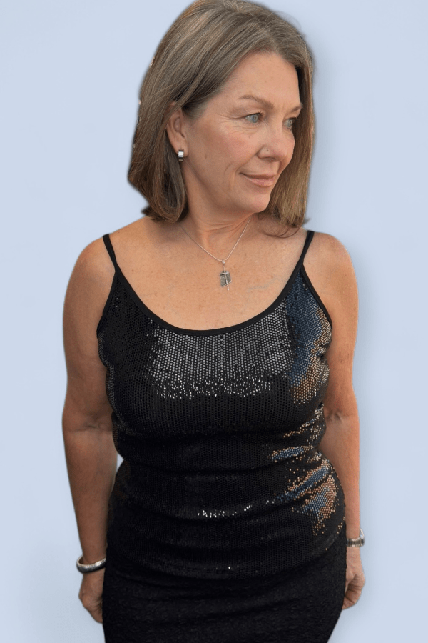 Woman wearing a black sequined dress against a light blue background