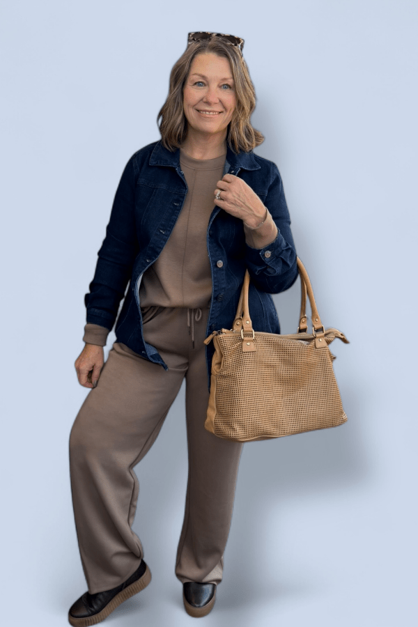 Woman holding a brown handbag against a light blue background