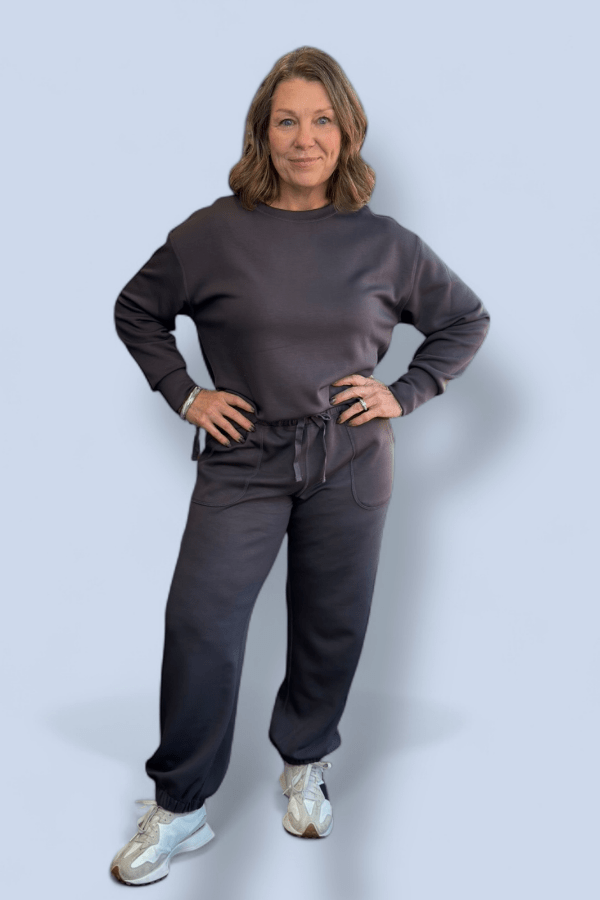 Woman wearing a gray tracksuit on a light blue background