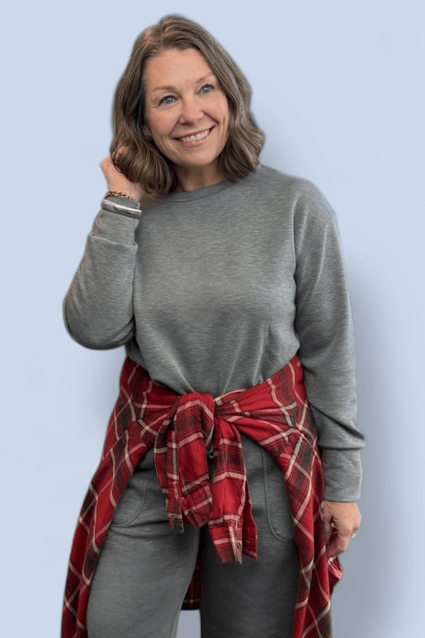 Woman wearing a matching jog set with a red plaid top tied around her waist.