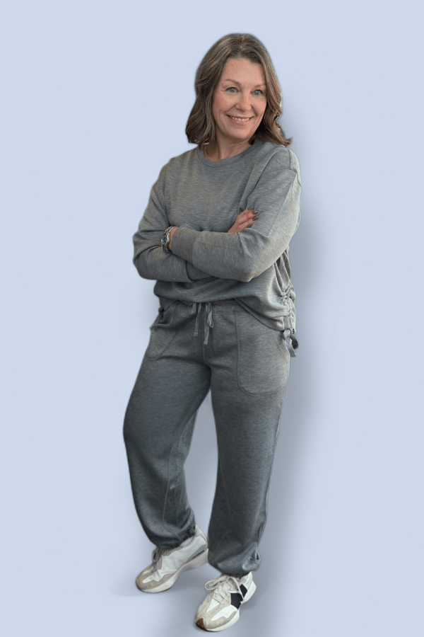 Woman wearing a gray sweatsuit and white tennis shoes.