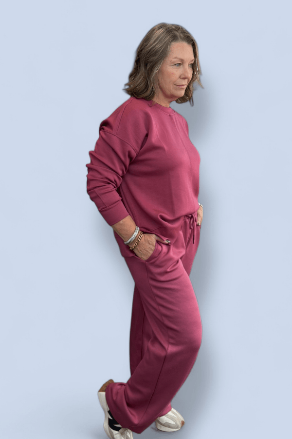 Woman wearing a pink tracksuit against a light blue background