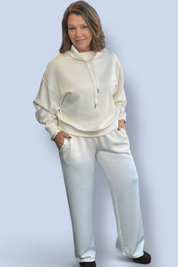 Woman wearing a cream-colored hoodie and pants on a light gray background