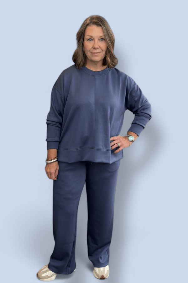 Woman wearing a navy blue outfit against a light gray background