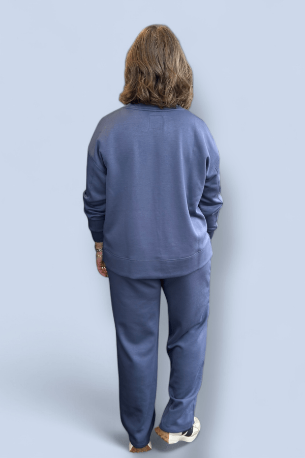 Person wearing a blue tracksuit against a light gray background