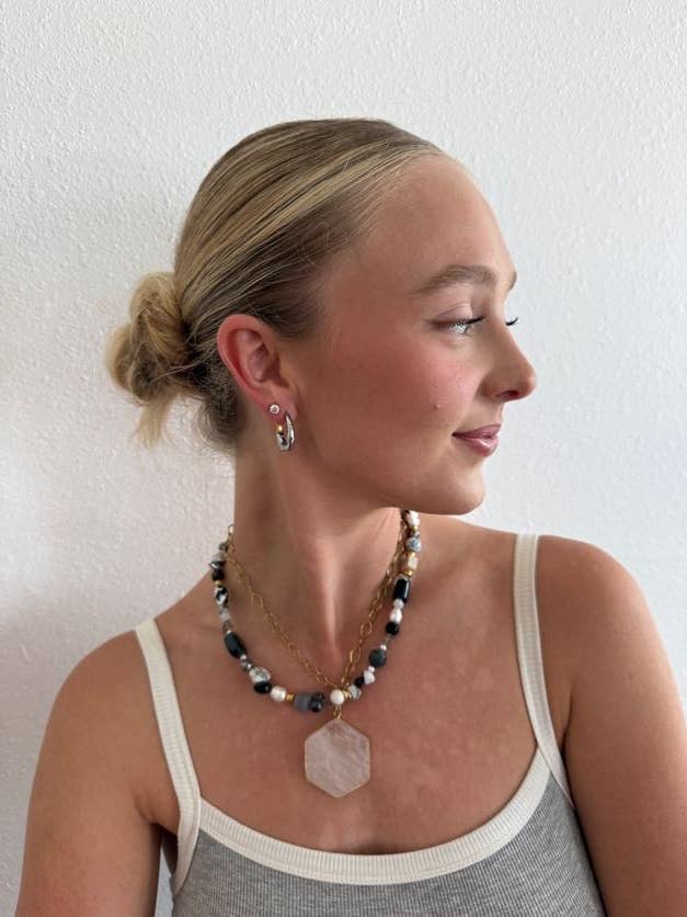 Woman wearing a necklace and earrings against a plain background