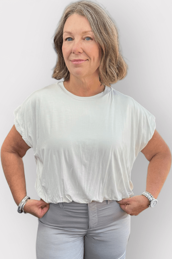Woman wearing a loose fit white top and gray bottoms.