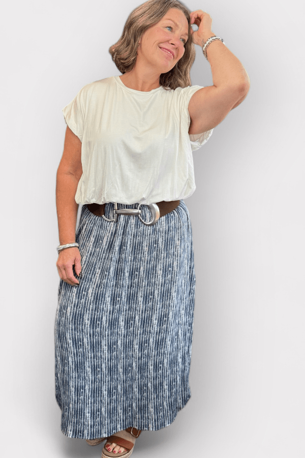 Woman wearing a white top with a blue maxi skirt.