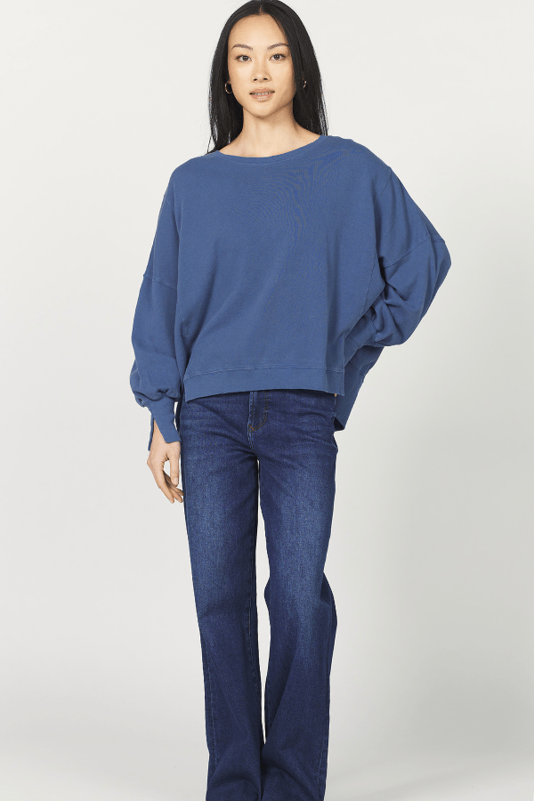 Woman wearing a blue sweater and jeans on a white background