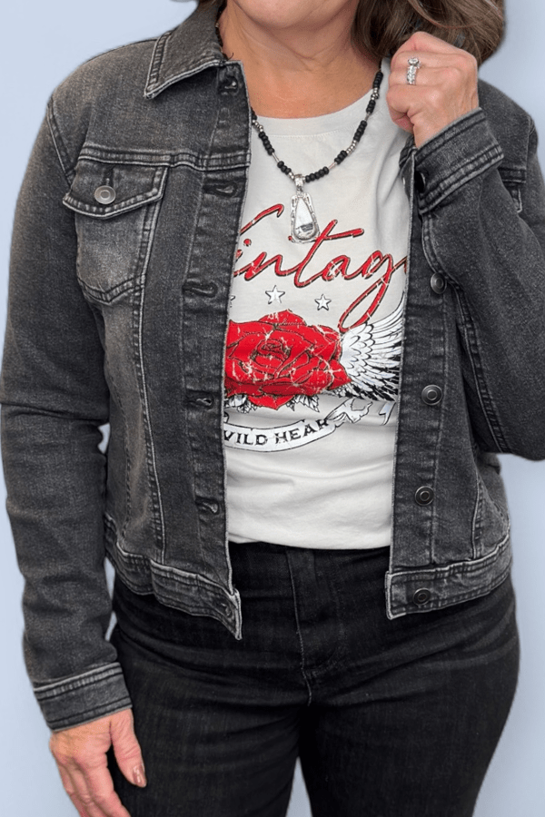 Close view of a black denim jacket worn over a graphic tee.