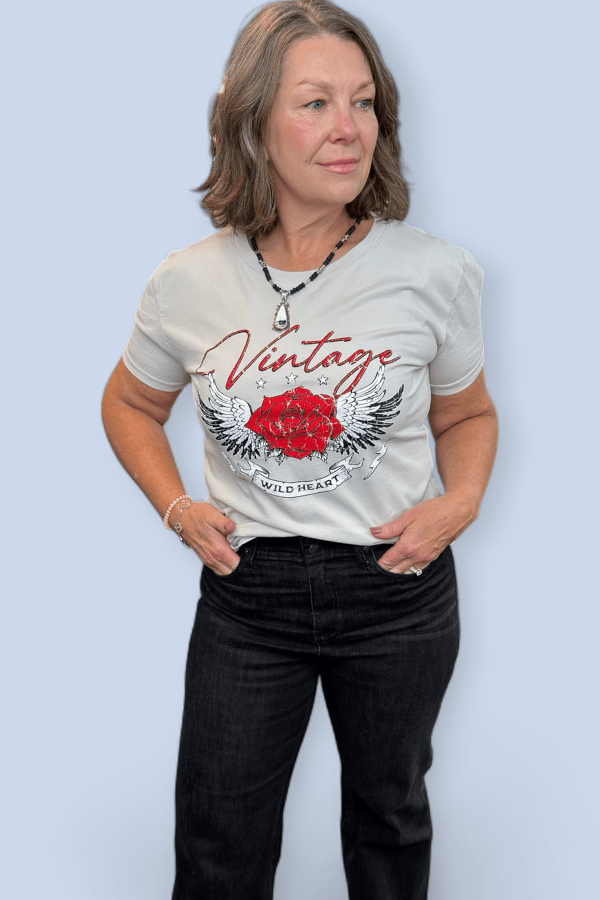 Woman wearing a gray t-shirt with a red rose and 'Vintage Wild Heart' design on a light blue background