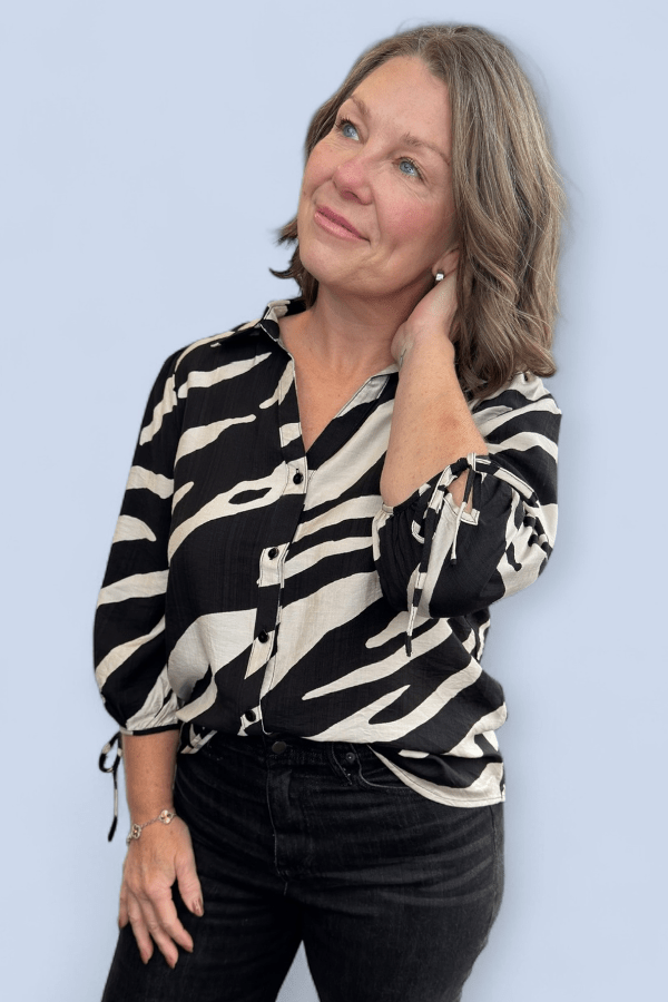 Woman wearing a zebra print blouse against a light blue background