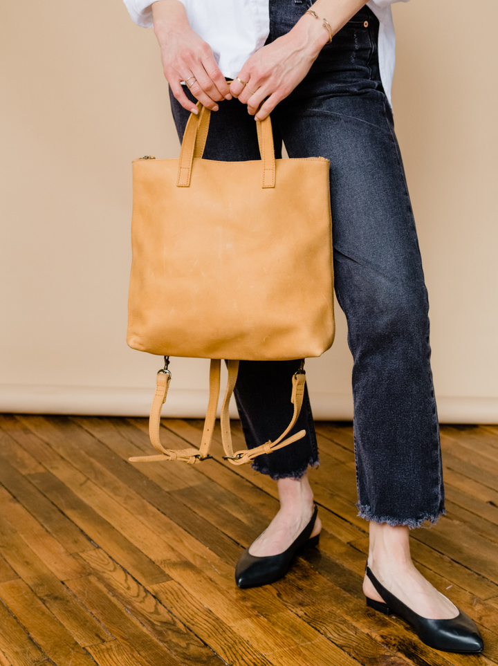 ABLE Abera Convertible Backpack in Cognac, removable backpack straps and antique brass buckles, back view on white