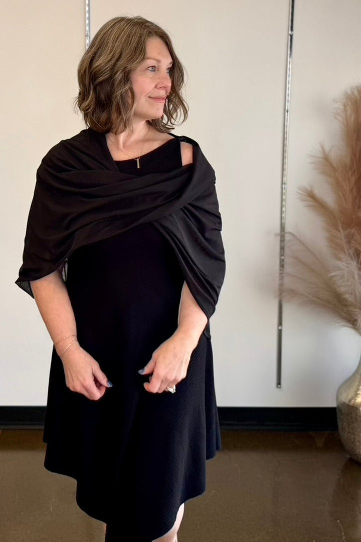 Woman looking in the distance wearing a black dress with a shawl.