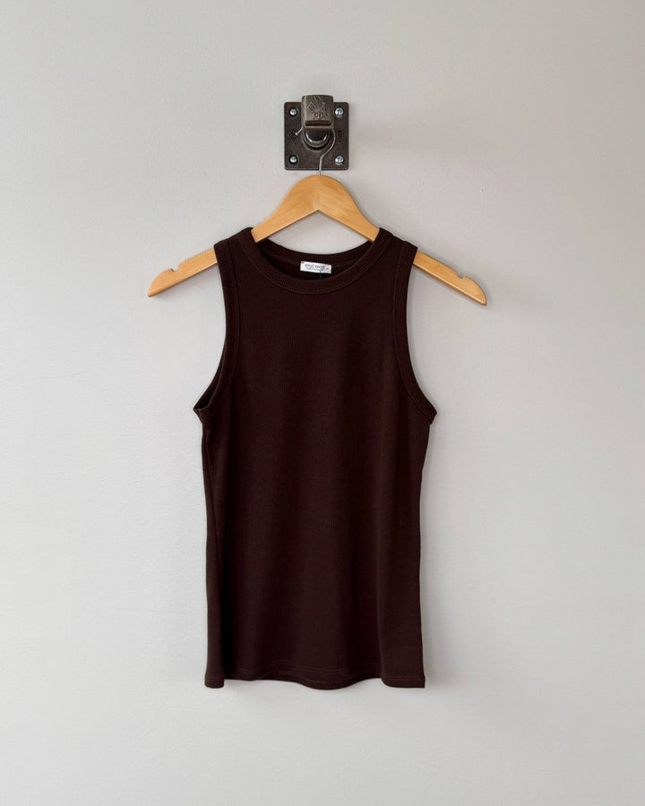 Brown tank top on a wooden hanger against a white wall