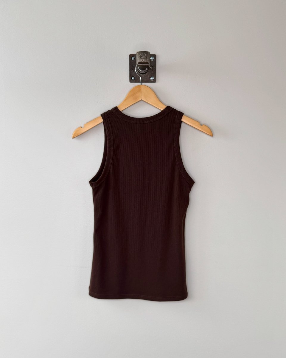 Brown tank top on a wooden hanger against a white wall