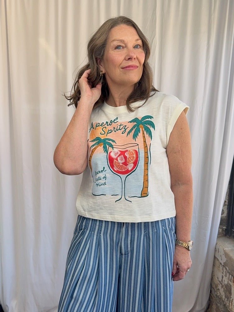 Woman wearing a graphic t-shirt with a tropical design against a white curtain background