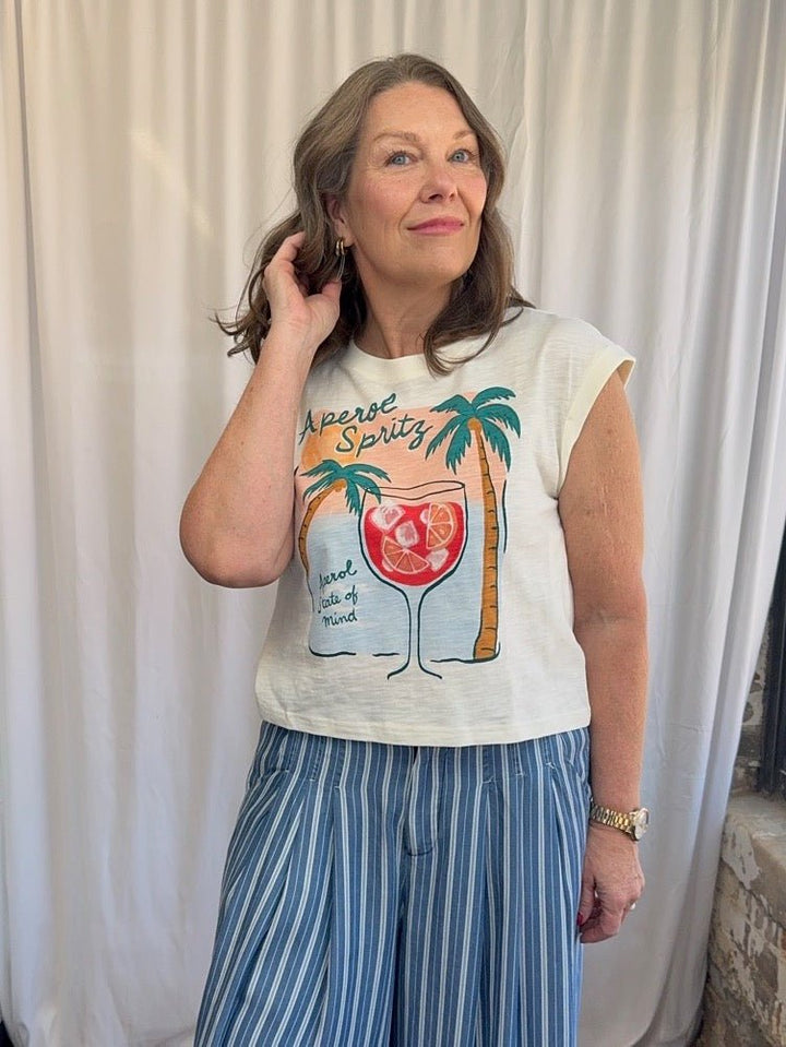 Woman wearing a graphic t-shirt with a tropical design against a white curtain background