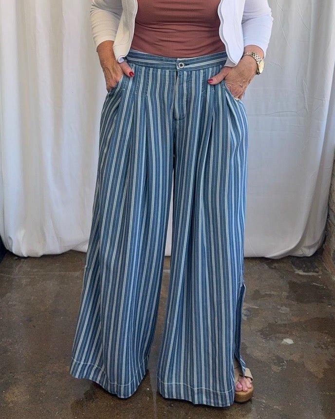 Blue and white stripe wide-leg pleated pants with single button waist and side pockets, close-up front view on model styled with mauve top and white cardigan
