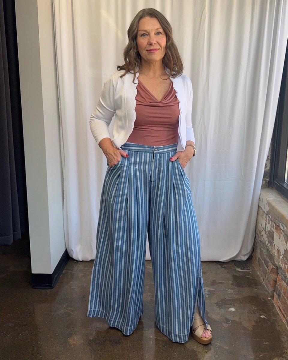 Blue and white stripe wide-leg pleated pants styled with mauve cowl neck tank and white open cardigan, hands in pockets, full length front view on model with wood block heel sandals
