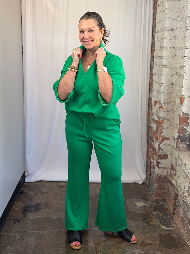 Carole Christian Scuba Modal Split-Collar Wide-Leg Set in Kelly Green, close-up front view with hands at collar showing open V-neck split-collar detail on model
