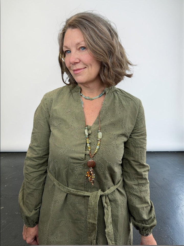 Woman wearing a green dress with a necklace against a white background