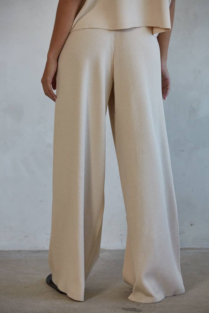 Woman wearing ivory ribbed pants shown from the rear.