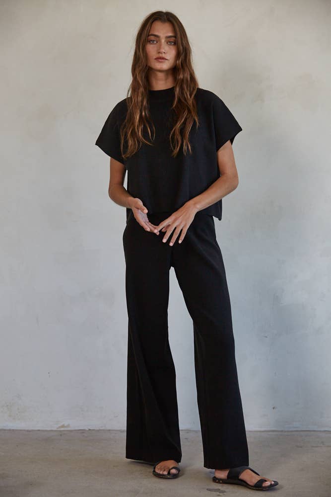 Woman wearing black ribbed pants shown with a matching top.