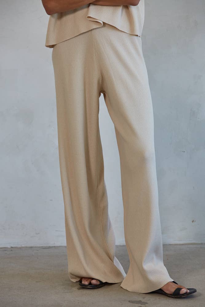 Woman wearing ivory ribbed pants shown from the waist down.