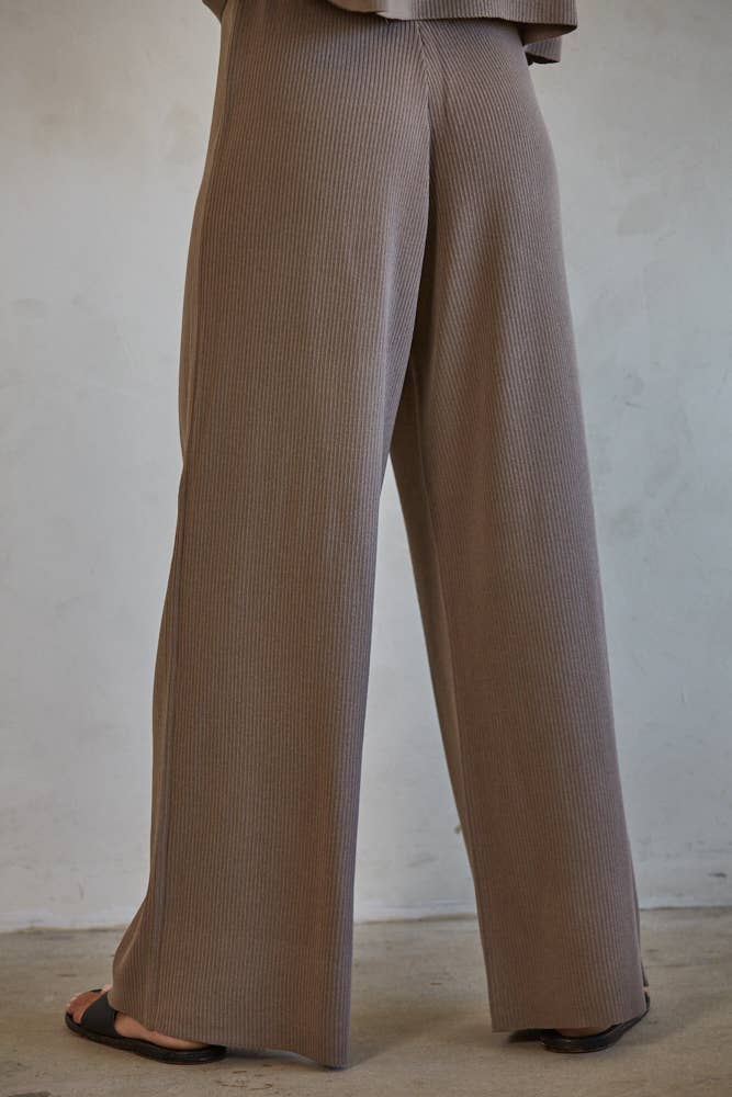 A pair of brown high-waisted wide leg pants with ribbed detailing, showing the back view.