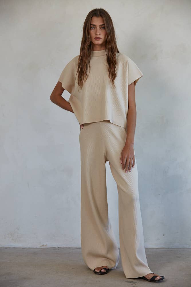 Woman wearing ivory ribbed pants shown as a set with a matching top.